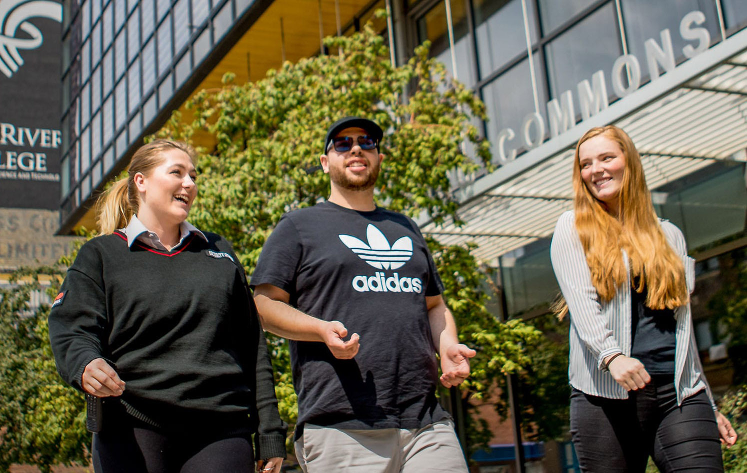 Happy students walking in front of the Princess Street campus building.