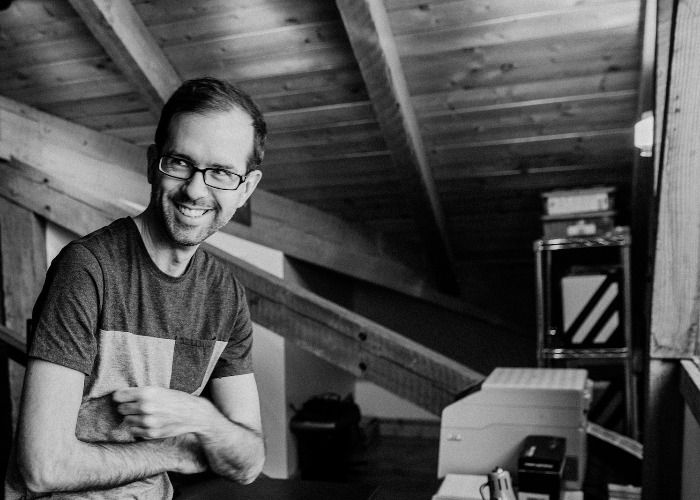 A black and white photo of Dan smiling and crossing his arms.
