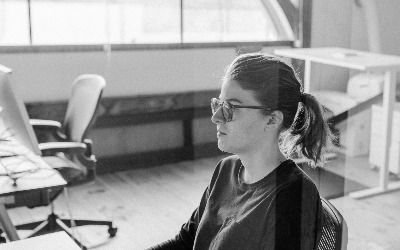 A black and white photo of a side profile of Nikki working at their computer.